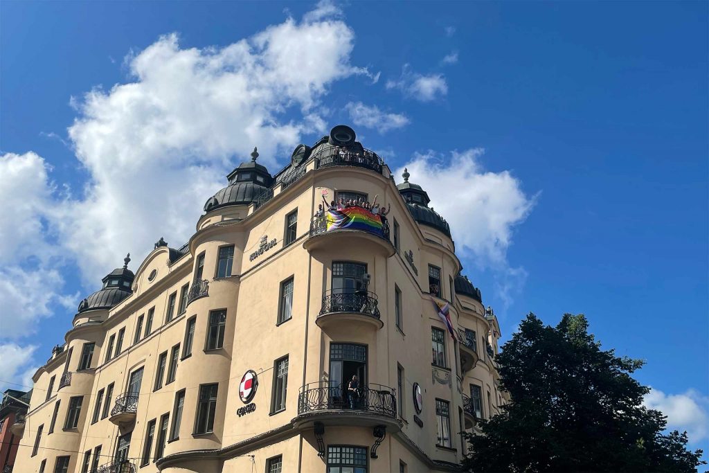 Our pride party waving from the balcony of Hotel Kung Carl above the Stockholm Pride 2023 parade. 