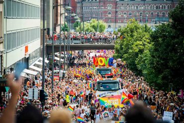 A Pride parade moving along a road in Stockholm