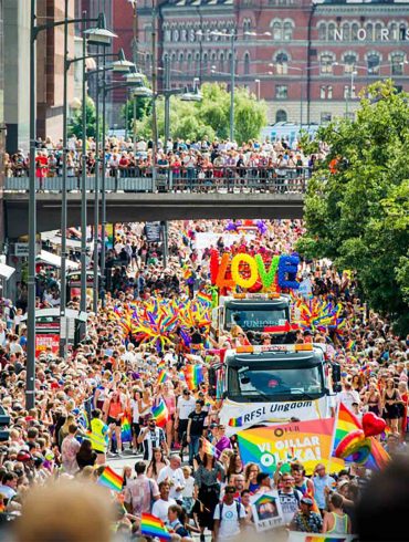 A Pride parade moving along a road in Stockholm
