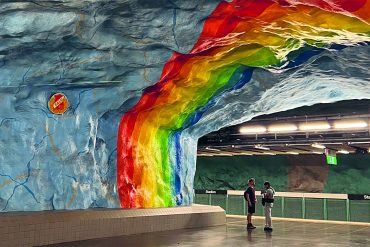 Two travellers stand under the rainbow metro station in Stockholm.