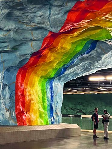 Two travellers stand under the rainbow metro station in Stockholm.