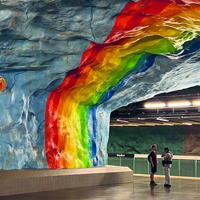 Two travellers stand under the rainbow metro station in Stockholm.