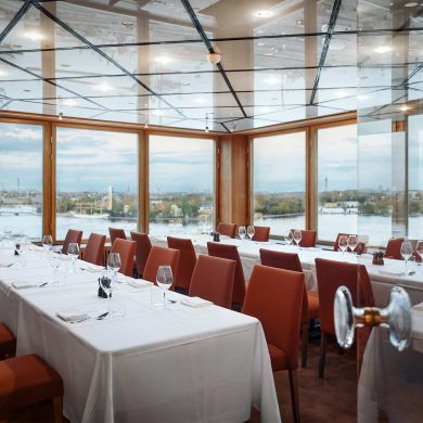 A private dining room with sprawling views of Stockholm. The chairs are red, and the tablecloths are white.