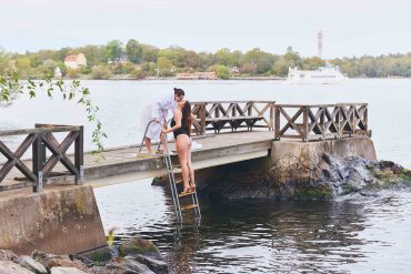 Two women kiss while getting out of a waterway near Hotel J. Stockholm work-life balance.